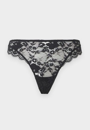 Μαύρο δαντελένιο στρινγκ με λουλουδένια σχέδια και κυματιστά άκρα, εμφανίζεται σε απλό ανοιχτό φόντο.