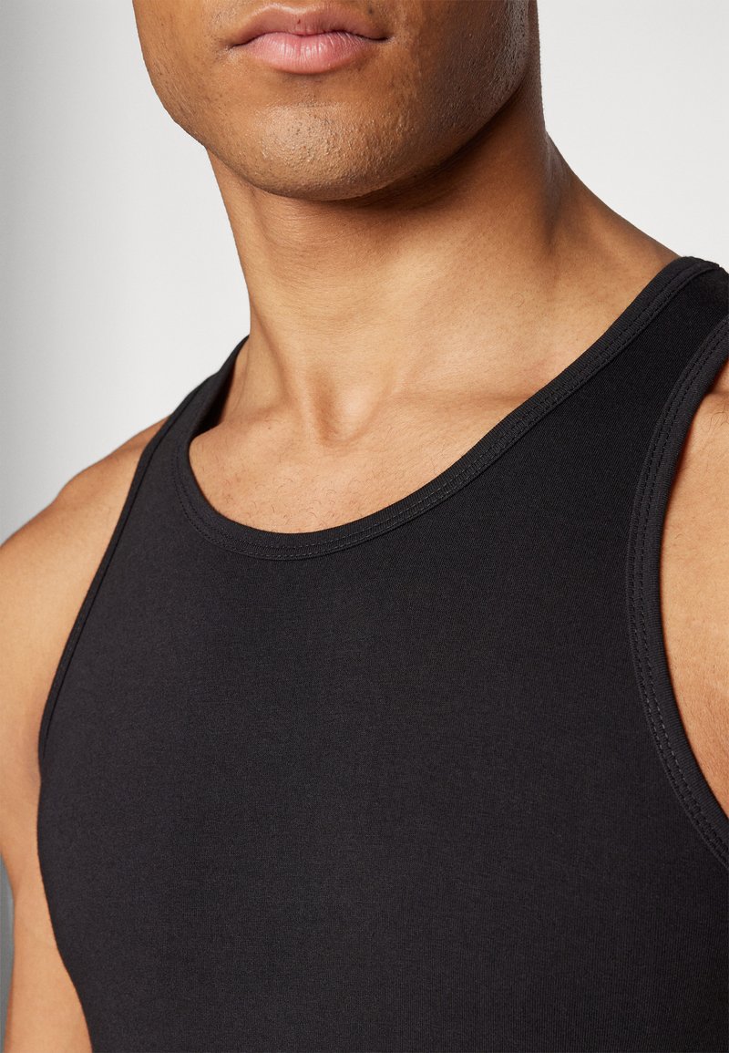 Czarny bawełniany top na ramiączkach z okrągłym dekoltem, ukazujący gładką teksturę i dopasowany krój, zaprezentowany na neutralnym tle.