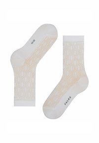 Gestrickte Socken mit einem Diamantmuster in hellbeige auf einem cremfarbenen Hintergrund. Mit dem „FALKE“-Logo auf der Sohle akzentuiert. Weiche Textur.