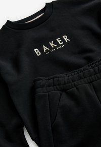 Sorte sweatshirt og sweatpants sæt lavet af blødt stof. Har ribbet halsudskæring og talje, med metallic "BAKER" logo på forsiden.