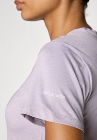 Light purple short-sleeve t-shirt made from soft fabric, featuring a logo on the left shoulder and a round neckline.