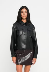 Svart skinnjakke med krage, knappefront, to brystlommer og en tettsittende design. Kombinert med et blankt burgunder skinnskjørt.