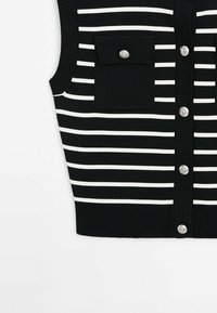 Veste noire sans manches en maille avec des rayures blanches horizontales, des boutons argentés sur le devant et une poche à rabat boutonnée sur la poitrine.