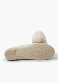 Scarpa in tessuto beige con punta arrotondata. Texture morbida, suola liscia con grip a motivo e marcatura della taglia 36 sul fondo.