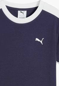 T-shirt violet avec col ras du cou blanc et accents aux épaules, avec un petit logo Puma blanc sur la poitrine. Tissu doux, design décontracté.