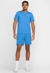 Maglietta sportiva blu a maniche corte abbinata a pantaloni corti coordinati. Entrambi i capi sono realizzati in tessuto leggero con una superficie morbida.