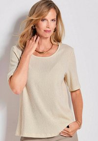 Beige Kurzarm-Top mit strukturiertem, geripptem Design, runder Ausschnitt und lockerer Passform. Keine bemerkenswerten Muster oder Akzente.
