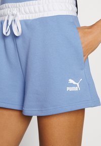 Light blue athletic shorts with a white elastic waistband, featuring a side pocket and a white Puma logo on the lower left leg.