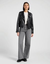 Chaqueta de biker negra de cuero sintético con cierre de cremallera, combinada con jeans de pierna ancha grises de cintura alta y botas negras de plataforma gruesa.