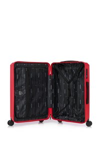 Valigia rigida rossa con interno in tessuto nero, design a righe e cinghie incrociate. Include una tasca con zip su un lato.