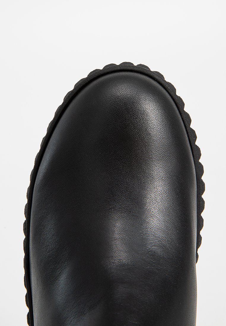 Schwarze Lederstiefel mit glatter Oberfläche, abgerundeter Spitze und gewellter Gummisohle. Das Design zeichnet sich durch einen minimalistischen Stil aus.