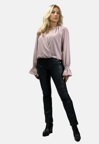 Bluzka z długim rękawem w kolorze mauve, z marszczonymi mankietami i krojem typu wrap, zestawiona z czarnymi, dopasowanymi spodniami oraz masywnymi czarnymi botkami za kostkę.