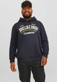 Navy-Hoodie mit weißem und gelbem Text "JACK&JONES AUTHENTIC DENIM WEAR CLASSICS", mit Kängurutasche und gerippten Bündchen.