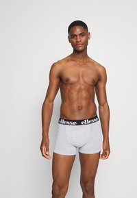 Grå bomullsboxershorts med svart midja som har vit logotext. Tättsittande design, slät textur och minimal detalj.