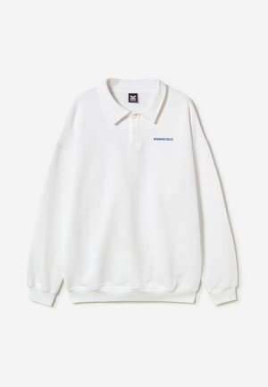 Λευκό μακρυμάνικο πόλο με ριμπ μανσέτες, γιακά με κουμπιά και μικρό ναυτικό μπλε κείμενο "MORNING CALLS" στο πάνω αριστερό μέρος του στήθους.