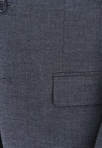 Ciemnoszara marynarka wykonana z teksturowanej tkaniny, z pojedynczym zapinaniem na guzik oraz kieszenią typu welt po lewej stronie z przodu.