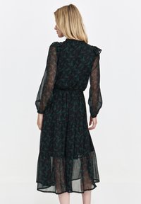 Black chiffon dress with a floral pattern in green and red, featuring long, puffed sleeves and a tiered hemline, cinched at the waist.