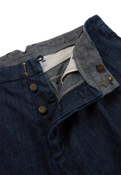 Denim pants with partially open button fly, visible striped inner lining, and metal button and hook fasteners.