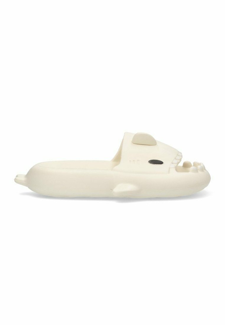 Sandalia de goma blanca en forma de cabeza de animal con ojos y detalles de dientes elevados. Presenta una textura suave y un diseño redondeado.