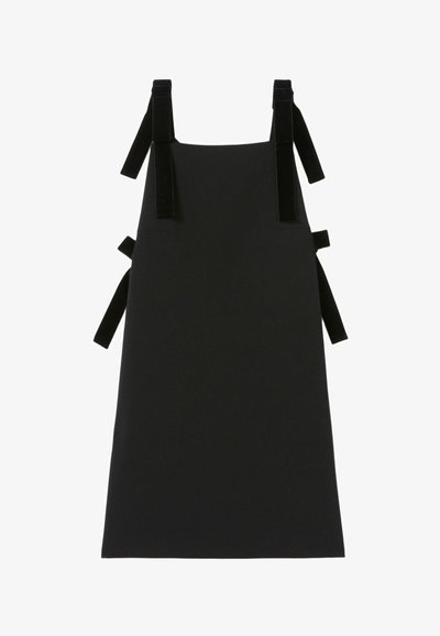 Vestito a grembiule senza maniche di colore nero con ampie spalline in velluto e lacci laterali, parte anteriore piatta, taglio dritto.
