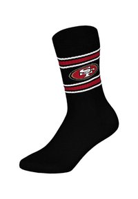 Czarna skarpeta typu crew z czerwono-białymi paskami i dzianym logo w owalnym kształcie po boku. Miękki, elastyczny materiał zapewniający komfort.