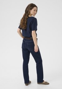 Mørkeblå denim jeans med lige pasform, et brunt bælte og en marineblå t-shirt med kortærmer. Outfitet har et rent, afslappet design.