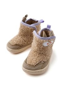 Botas de tobillo beige de felpa con una textura suave, acentos de ante, ribetes morados y detalles de ojos juguetones. Diseñadas para la comodidad y el calor.
