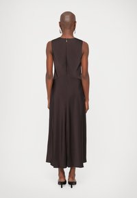 Kätsemanikute midi kleit tumespruunist kangast, sirge siluett, taga tõmblukuga ja peente õmbluste detailidega. Elegantne ja voolav langus.