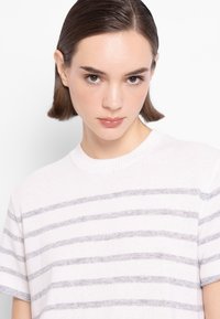 Biały sweter w paski z szarymi poziomymi paskami, okrągłym ściągaczem na szyi i krótkimi rękawami, wykonany z miękkiego, lekkiego materiału.