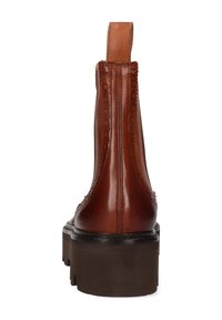 Botín de cuero marrón con detalles de brogue, tirador en la parte trasera y suela de goma negra gruesa, mostrado desde la vista trasera.