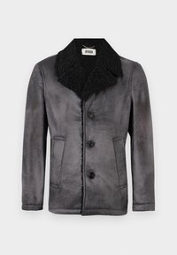 Cappotto di lana grigio con colletto in shearling nero, dotato di quattro bottoni, due tasche laterali e una superficie testurizzata. Etichetta del marchio visibile all'interno.
