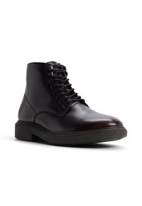 Botas de cuero marrón hasta el tobillo con punta redonda, cordones frontales y suela de goma texturizada. Presenta una superficie lisa y un diseño discreto.