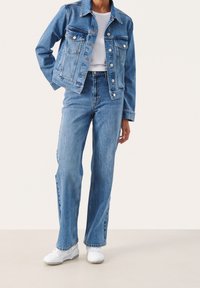 Jeansjacka med två framfickor, långa ärmar och ljusblå färg. Kombinerad med högmidjade ljusblå jeans och vita sneakers.