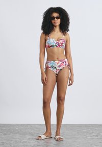 Divdaļīgs bikini komplekts ar ziedu rakstu rozā, zilā un zaļā krāsā. Augšdaļai ir mīlestības sirds formas izgriezums; apakšdaļa ir ar augstu vidukli.