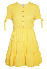 Žluté šaty s krátkým rukávem, kulatým výstřihem, zapínáním na knoflíky a vrstvenou sukní. Obsahují vázací detaily na rukávech a měkkou texturu.