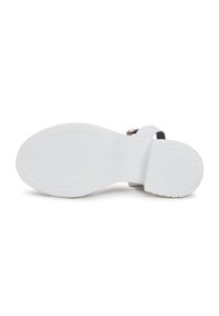 Semelle de sandale blanche avec une texture antidérapante, arborant un design élégant et un coussin de pied. Sangle ajustable avec détail de boucle métallique.