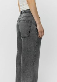 Jeans a vita alta, a gamba dritta, in denim grigio sbiadito con tasche posteriori e un sottile dettaglio di cucitura. Tessuto testurizzato con una vestibilità comoda.
