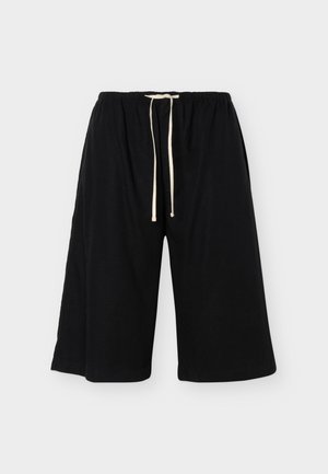 Μαύρα, άνετα σορτς μέχρι το γόνατο με ελαστική μέση και λευκό κορδόνι, εμφανιζόμενα σε απλό φωτεινό φόντο.