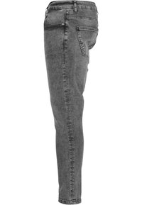 Jeans de mezclilla gris, ajuste slim con cinco bolsillos, cierre con cremallera y detalles de costura visibles en las costuras. Textura suave, diseño de pierna cónica.