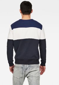 Sudadera con bloque de color en azul marino y blanco, con cuello redondo, mangas largas y puños y dobladillo acanalados, fabricada con una mezcla de algodón.