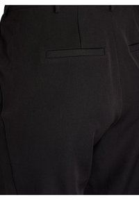 Črne hlače iz gladkega materiala, ki imajo prilegajočo zasnovo, dva zadnja žepa in subtilne šive ob šivih.