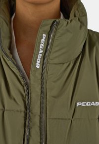 Olivově zelená péřová bunda s vysokým límcem, kovovým zipem a bílou výšivkou loga "PEGADOR" na přední straně. Hladká nylonová textura.