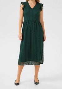 Tealfärgad klänning med V-ringning, korta volangärmar och åtsittande midja. Tyget har ett geometriskt mönster och en spetsdetalj i fållen.