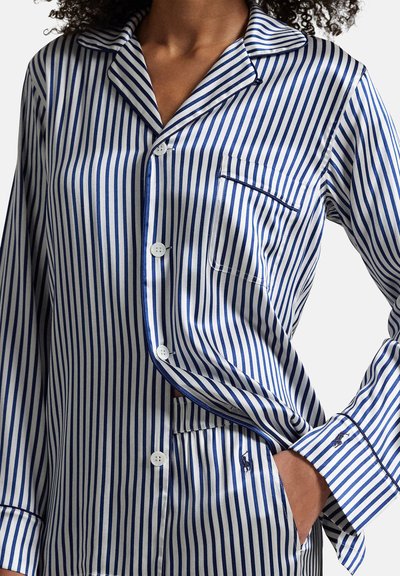 Blauw-wit gestreept pyjamaset van soepel stof, met knoopsluiting, borstzak en geborduurd logo op de manchetten.