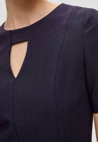 Námořnické modré šaty se strukturovaným designem, s vykrojením na krku a krátkými rukávy. Hladká textura s jemnými švy.