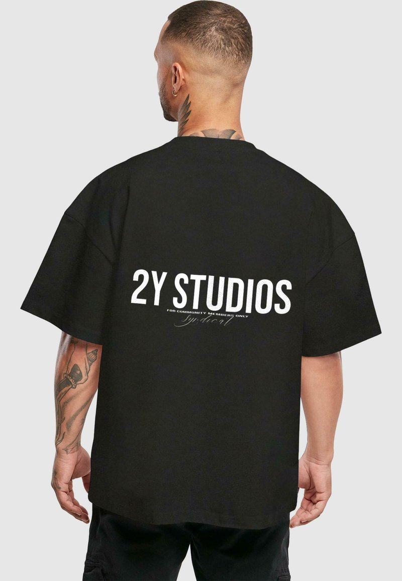 Juoda persiaugusi marškinėlių su trumpomis rankovėmis, ant nugaros raudonai su baltu tekstu "2Y STUDIOS".