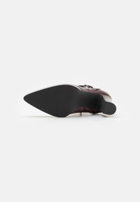 Chaussure à talon haut en cuir bordeaux avec un bout pointu et une semelle noire texturée. Présente un design élégant et un talon étroit.