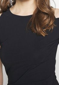 Czarna bluzka o designie bez ramiączek, wykonana z gładkiego materiału. Posiada subtelne marszczenia i prosty dekolt, co zapewnia elegancki wygląd.