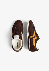 Zapatillas deportivas de ante marrón con detalles en naranja, paneles texturizados y suela de goma blanca. Diseño con cordones, cuello y lengüeta acolchados.