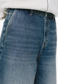 Jeans in denim blu con una finitura sbiadita, caratterizzati da un vita alta, un classico design a cinque tasche e cuciture robuste lungo le cuciture.